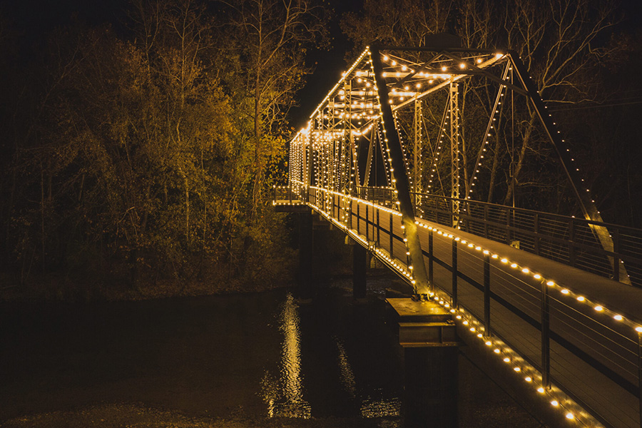 walking bridge lit up by lights outlining the frame of the bridge