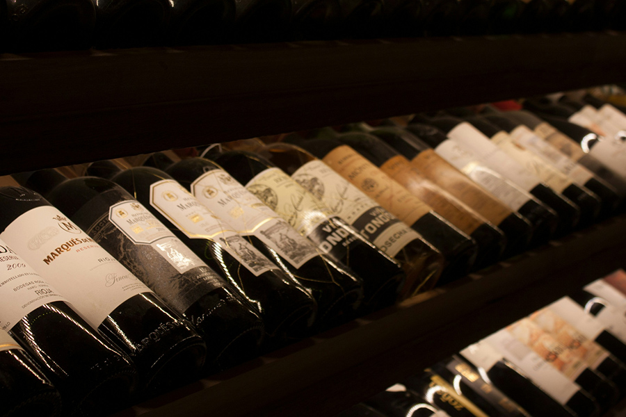 a row filled with distinct wine bottles and the shine of an overhead light