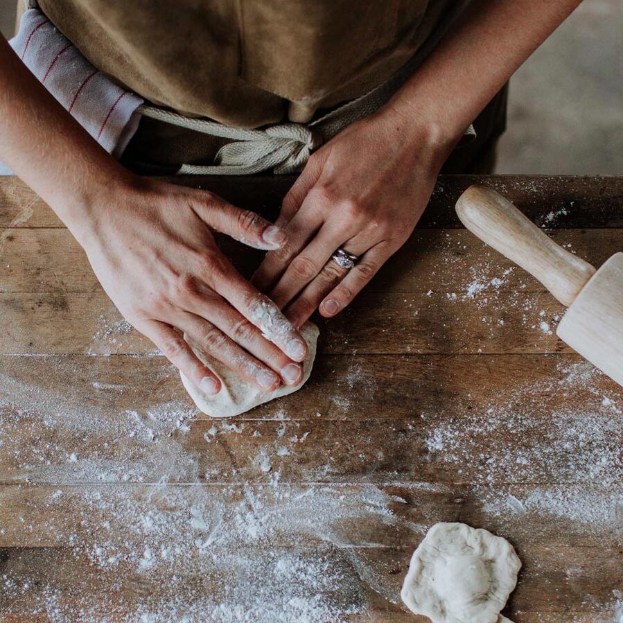 workshops-finley-farms-header person stretching out dough by hand on a flour dusted wood surface